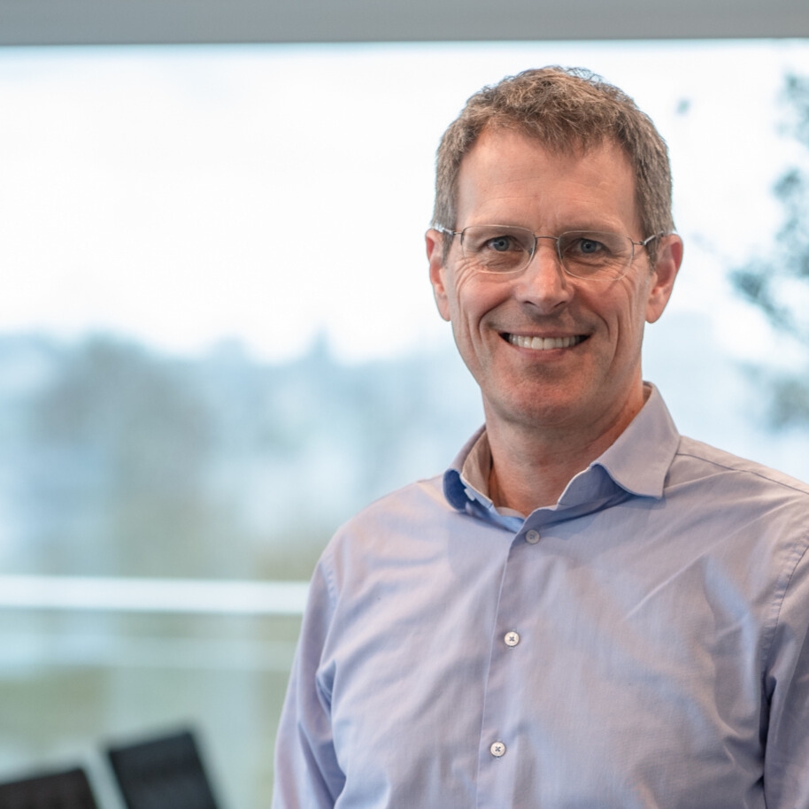 Geschäftsführer der LWLcom GmbH Frank Holmes. Er hat kurzes grau-blondes Haar, trägt ein hellblaues Hemd und steht vor einem unscharfem Hintergrund.